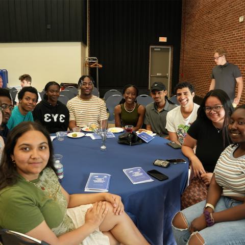 Student org sitting at table smiling at camera.